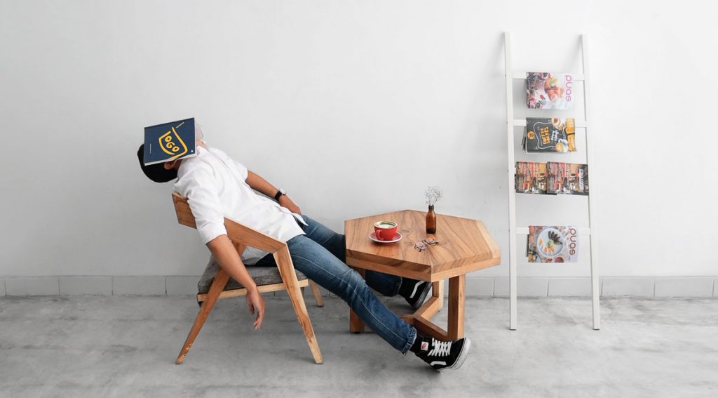 a person sleeping in a chair with a book on his face.